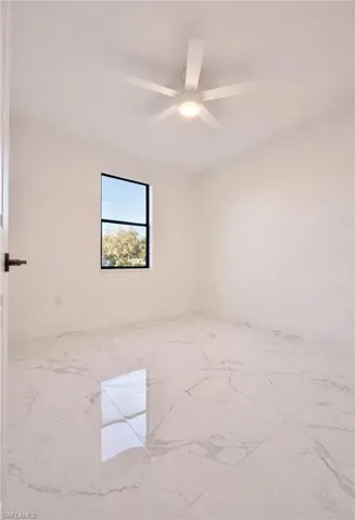 Empty room featuring light marble finish flooring and ceiling fan