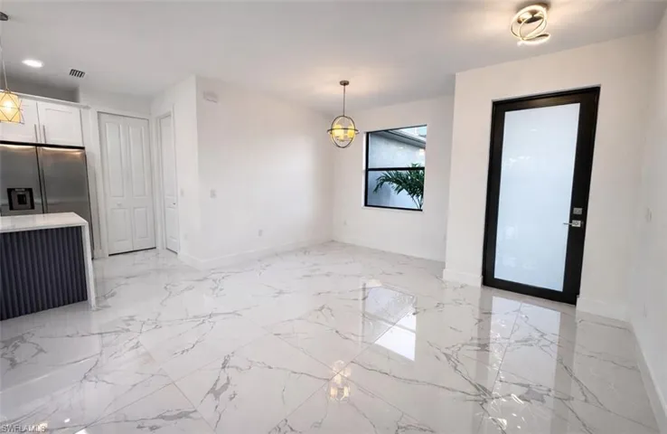 Unfurnished dining area with light marble finish floors and baseboards
