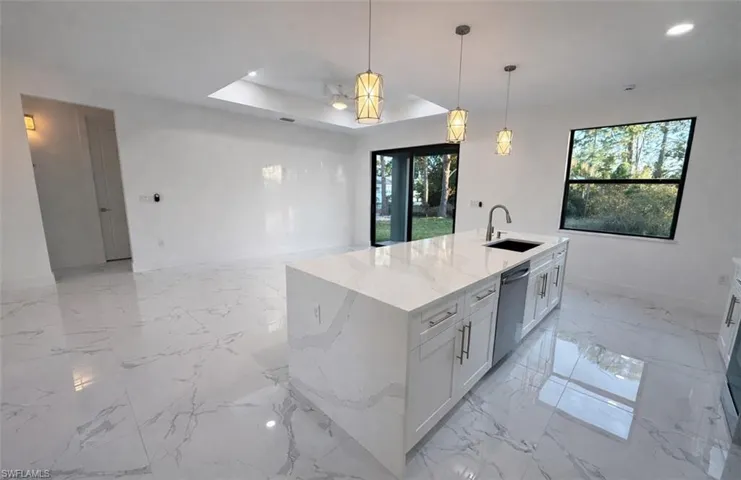 Kitchen featuring light stone countertops, pendant lighting, open floor plan, white cabinetry, and recessed lighting