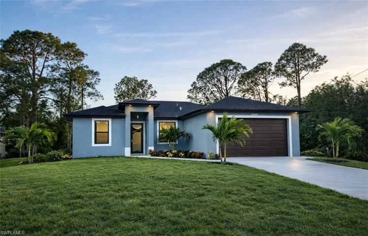 View of front facade with a front lawn, stucco siding, concrete driveway, and a garage