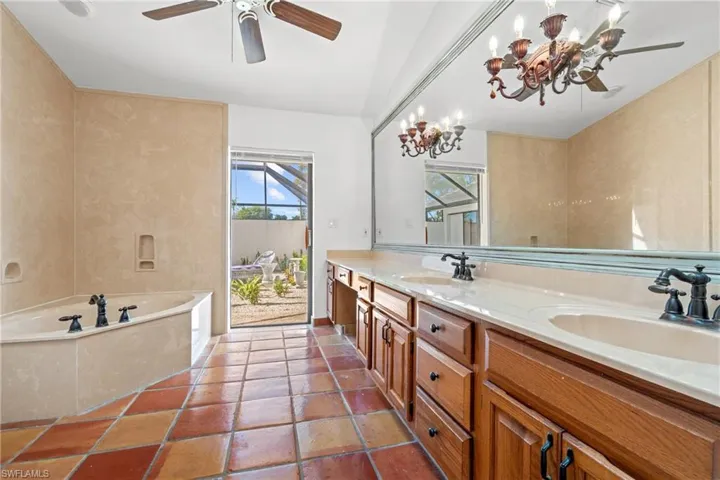 Bathroom with double vanity, a garden tub, ceiling fan, and a chandelier