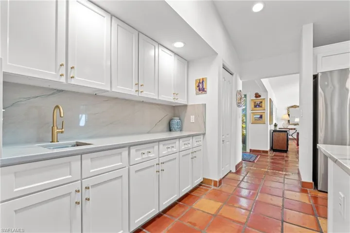 Kitchen with white cabinets, freestanding refrigerator, decorative backsplash, recessed lighting, and light stone countertops