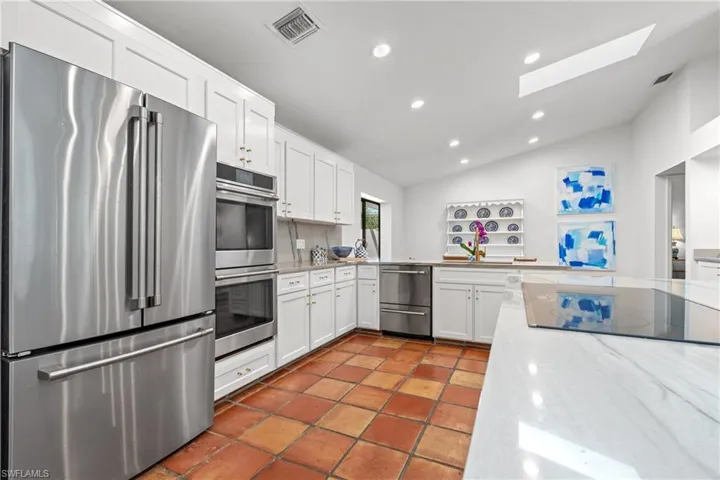 Kitchen with appliances with stainless steel finishes, white cabinetry, a skylight, recessed lighting, and lofted ceiling