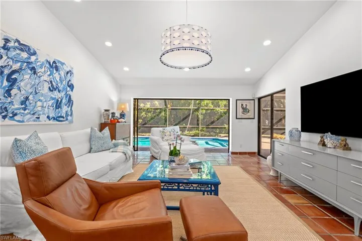 Tiled living area with lofted ceiling, recessed lighting, and a sunroom
