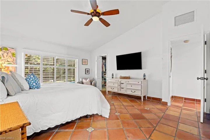 Bedroom featuring lofted ceiling, a spacious closet, ceiling fan, and tile patterned floors