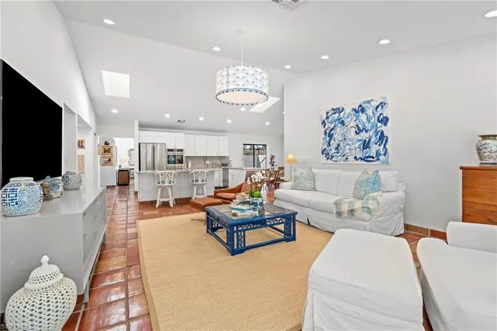 Living room featuring light tile patterned floors, high vaulted ceiling, recessed lighting, and a skylight