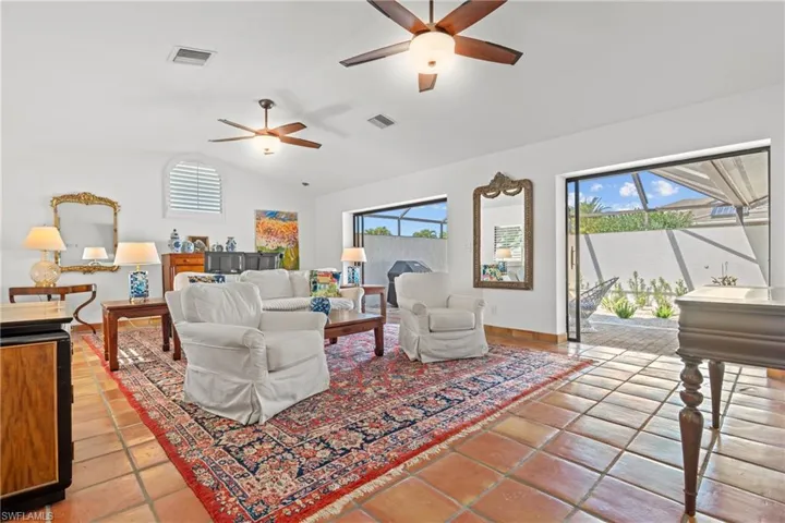 Living room featuring vaulted ceiling, light tile patterned floors, healthy amount of natural light, and a ceiling fan