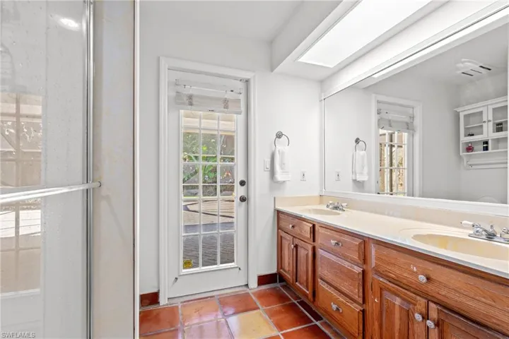 Bathroom with double vanity, a skylight, and a shower stall