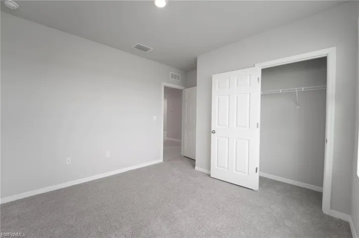Unfurnished bedroom featuring light carpet and a closet