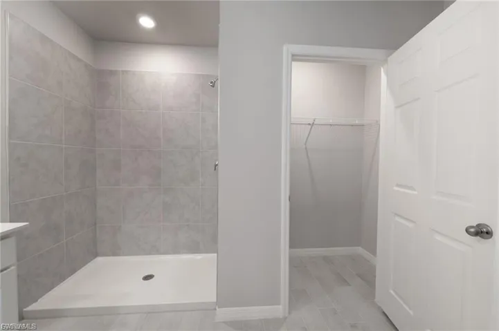 Full bathroom with a shower stall, a walk in closet, wood tiled floors, and vanity