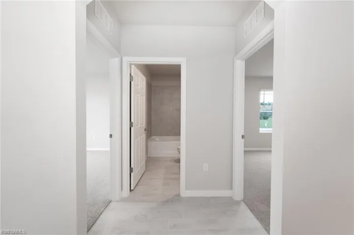 Hallway featuring light carpet and baseboards