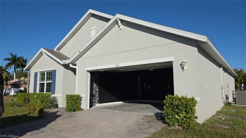 View of side of property featuring stucco siding, decorative driveway, and an attached garage