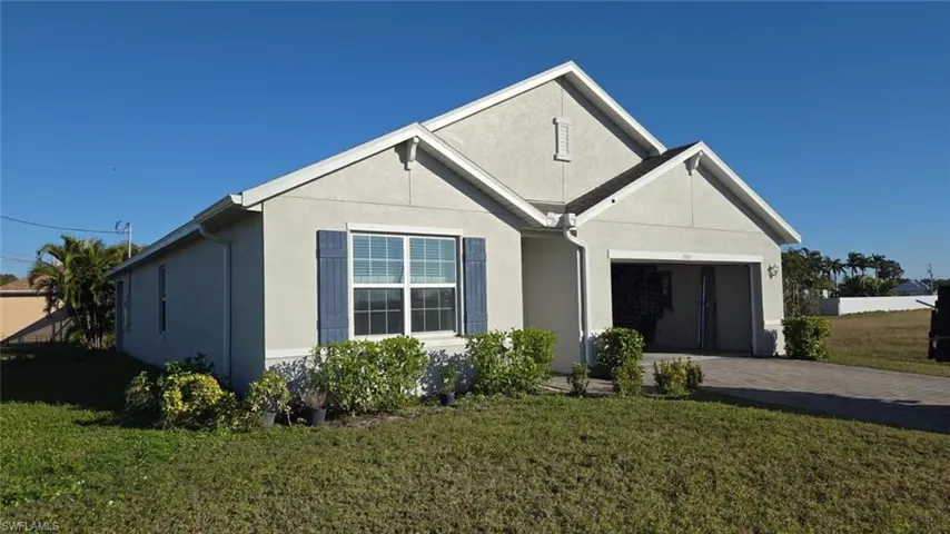 View of front of house featuring stucco siding, decorative driveway, a front yard, and an attached garage