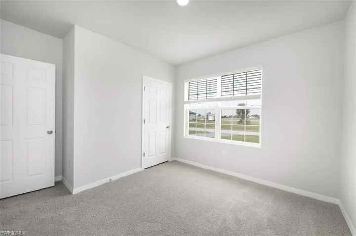 Unfurnished bedroom with light colored carpet and baseboards