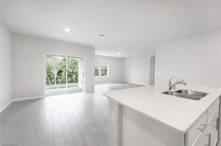 Kitchen with an island with sink, arched walkways, wood tiled floors, open floor plan, and white cabinetry
