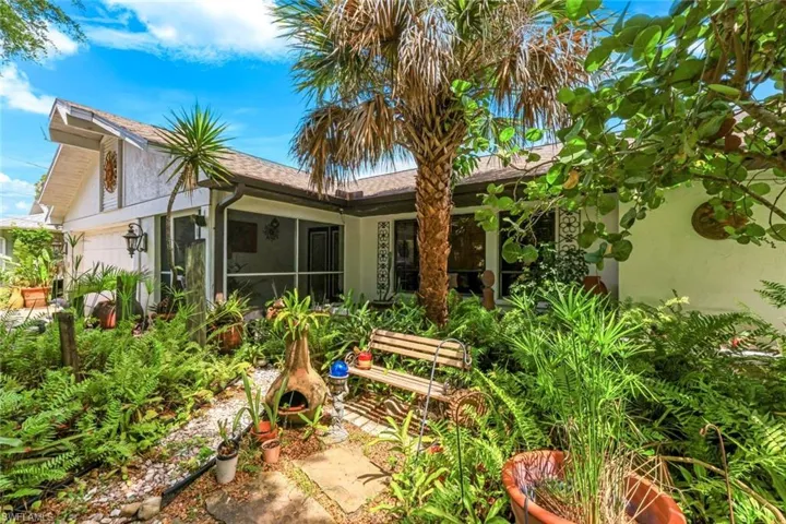 Back of property featuring stucco siding, a sunroom, and roof with shingles