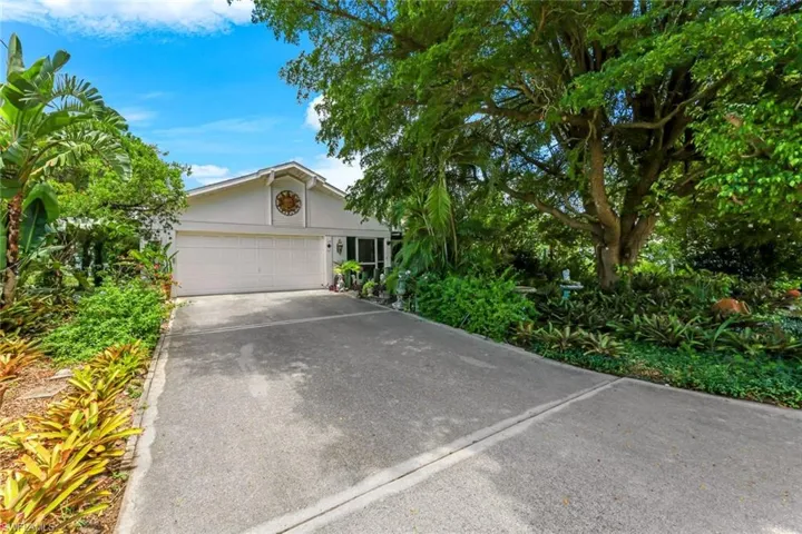 View of front of property featuring stucco siding, an attached garage, and driveway