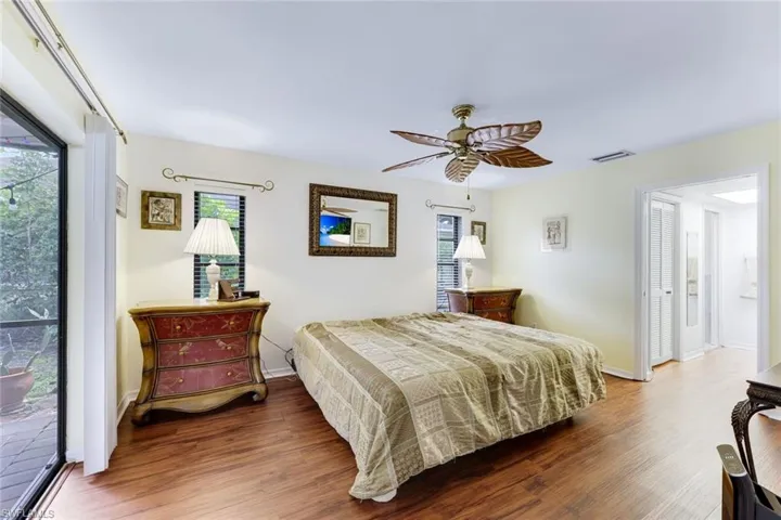 Bedroom featuring wood finished floors, multiple windows, access to outside, and ceiling fan