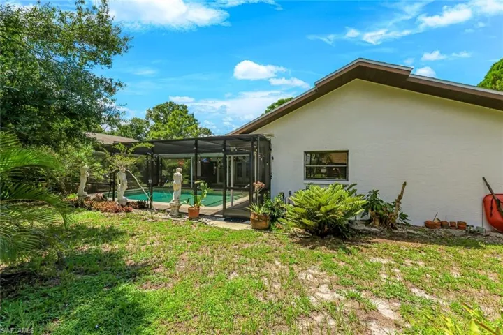 Rear view of property featuring stucco siding, an outdoor pool, a lanai, and a lawn
