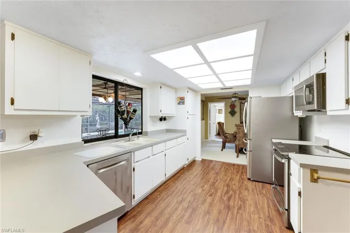 Kitchen with appliances with stainless steel finishes, light countertops, light wood-style floors, ceiling fan, and a textured ceiling