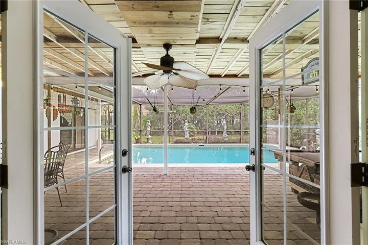 Outdoor pool with a patio area, glass enclosure, and ceiling fan