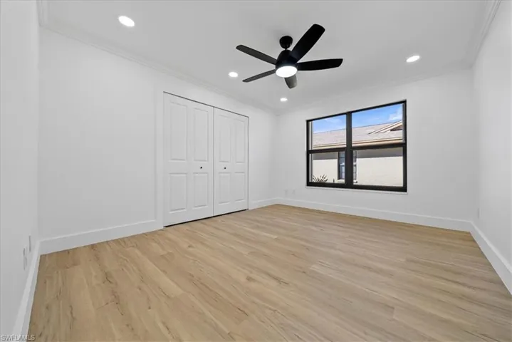 Unfurnished bedroom with recessed lighting, a ceiling fan, crown molding, light wood finished floors, and a closet