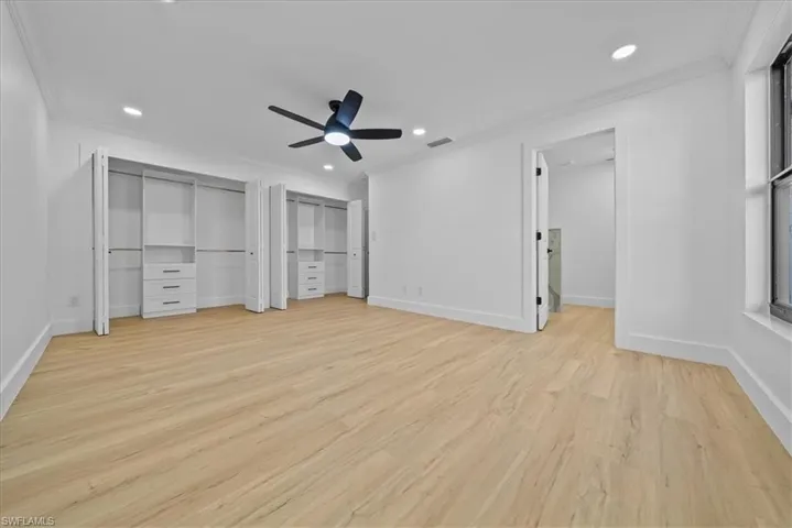 Unfurnished bedroom with multiple closets, crown molding, light wood-style flooring, recessed lighting, and a ceiling fan