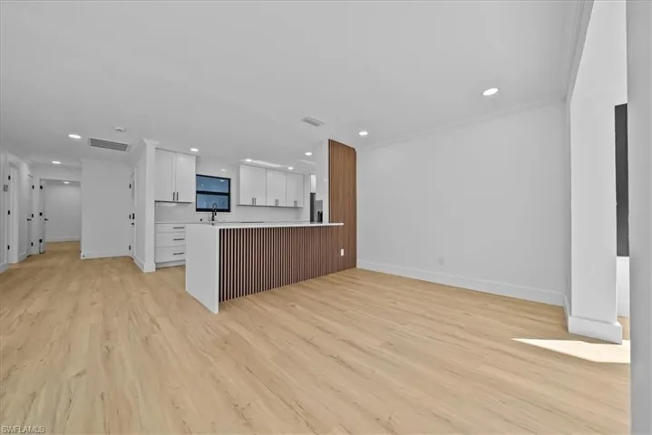 Kitchen featuring light countertops, white cabinets, a peninsula, open floor plan, and light wood finished floors