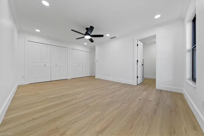 Unfurnished bedroom featuring multiple closets, ornamental molding, light wood-style flooring, recessed lighting, and a ceiling fan