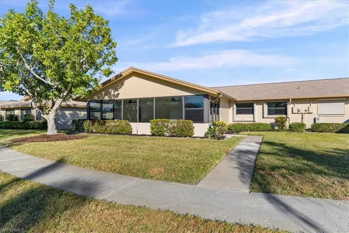 Ranch-style house featuring a front lawn, stucco siding, and a sunroom