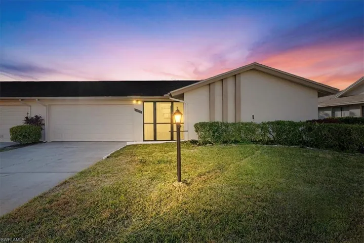 Mid-century modern home with driveway, a front yard, stucco siding, and a garage