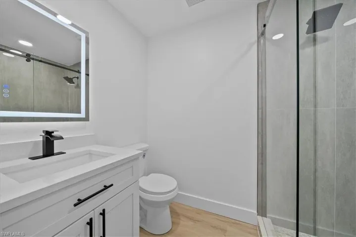 Full bath with vanity, a shower stall, and light wood finished floors