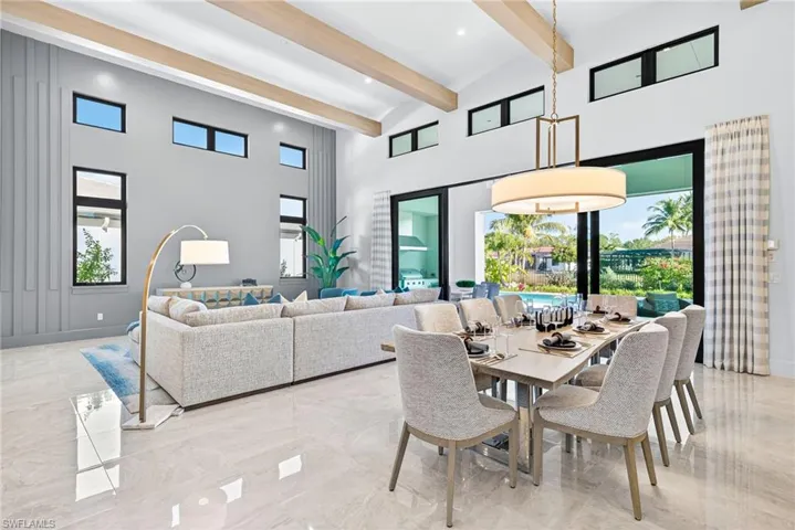 This stunning open-concept great room showcases soaring ceilings with elegant wood beams and an abundance of natural light streaming through