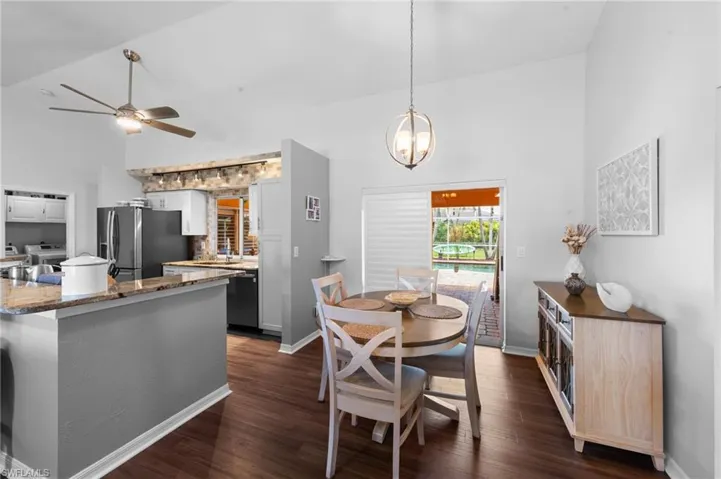 Dining space featuring a ceiling fan, dark wood finished floors, high vaulted ceiling, and a chandelier