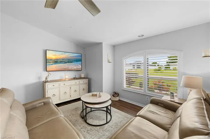 Living room with lofted ceiling, dark wood-style flooring, and a ceiling fan