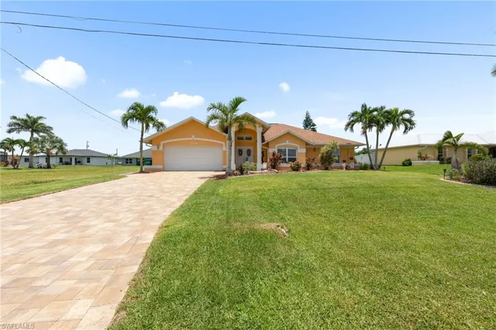 View of front of property with an attached garage, stucco siding, decorative driveway, and a front lawn
