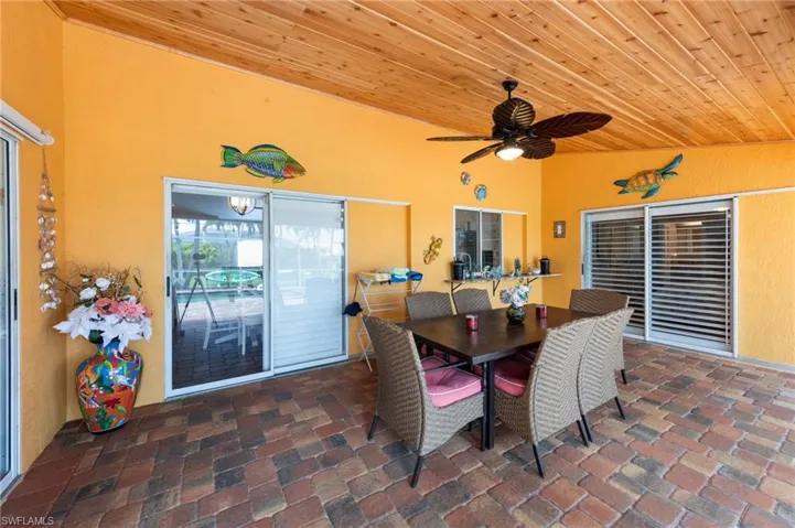 Dining space with wood ceiling, ceiling fan, brick floors, and high vaulted ceiling