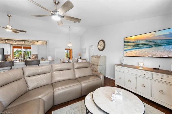 Living area featuring ceiling fan, dark wood-type flooring, lofted ceiling, and plenty of natural light