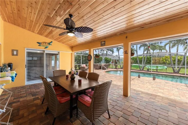 View of patio with ceiling fan, glass enclosure, and outdoor dining space