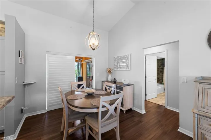Dining space featuring high vaulted ceiling, dark wood-style floors, and a chandelier