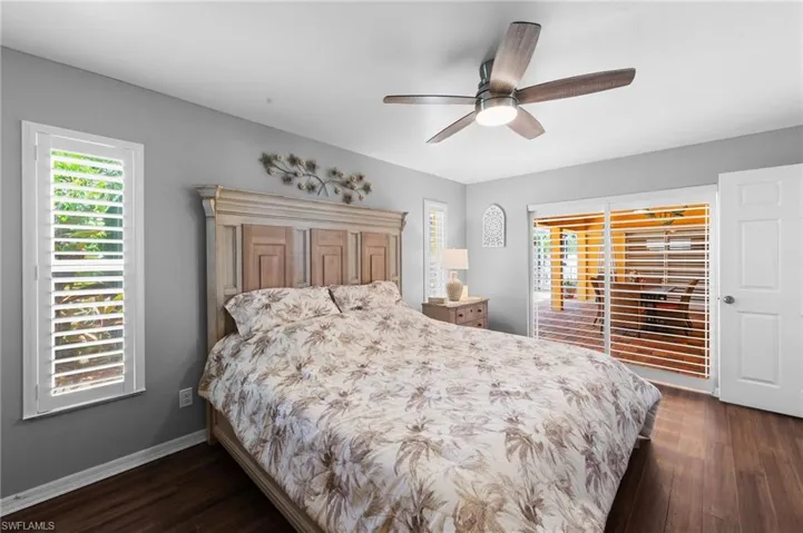 Bedroom with dark wood-style flooring, multiple windows, and ceiling fan