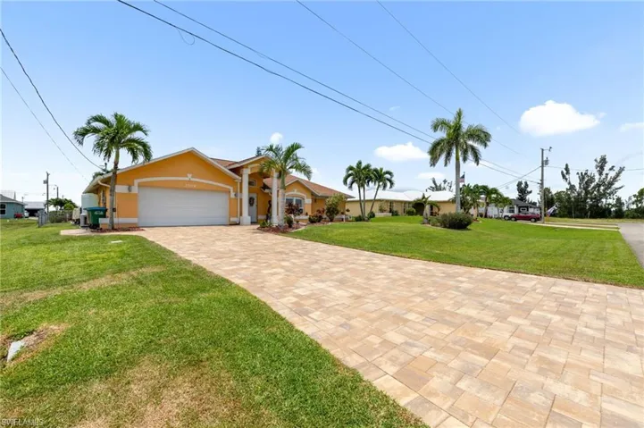 View of front of home featuring a front lawn, an attached garage, stucco siding, and decorative driveway