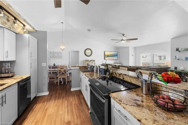 Kitchen featuring a ceiling fan, range with electric stovetop, light wood finished floors, lofted ceiling, and dishwasher