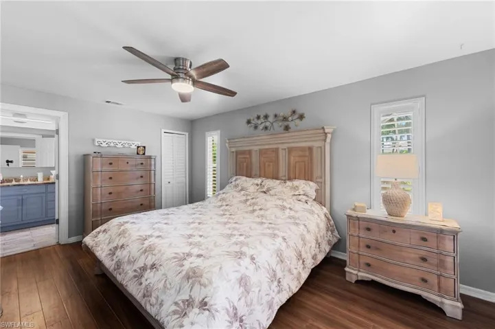 Bedroom with dark wood finished floors, multiple windows, a closet, and ensuite bathroom