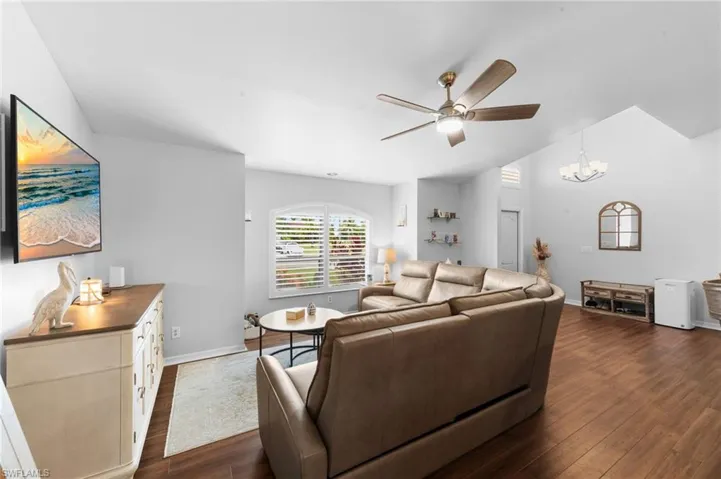Living area featuring ceiling fan, dark wood finished floors, a chandelier, and vaulted ceiling