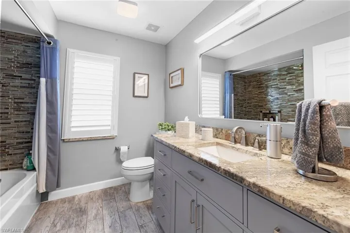 Full bathroom featuring vanity, wood finished floors, healthy amount of natural light, and shower / tub combo with curtain
