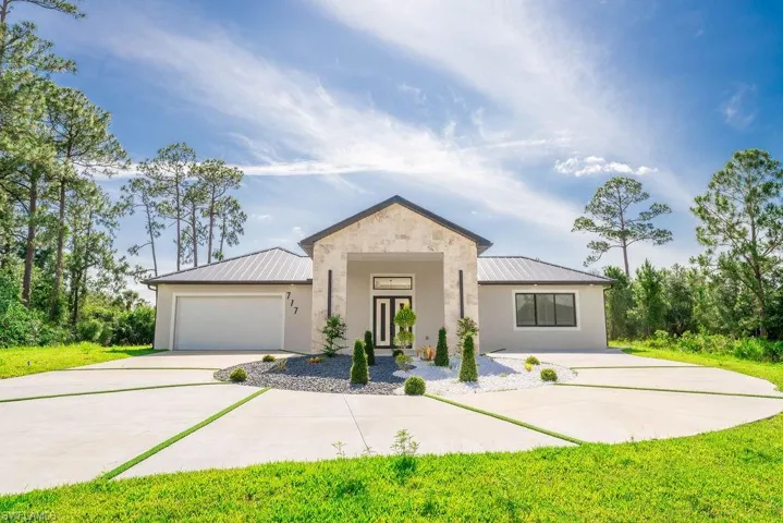 View of front facade with a metal roof, driveway, and a standing seam roof