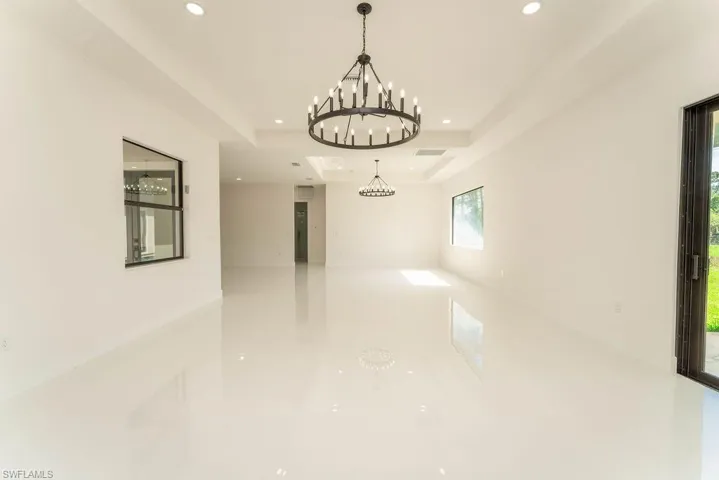 Unfurnished room with a tray ceiling, recessed lighting, and a chandelier