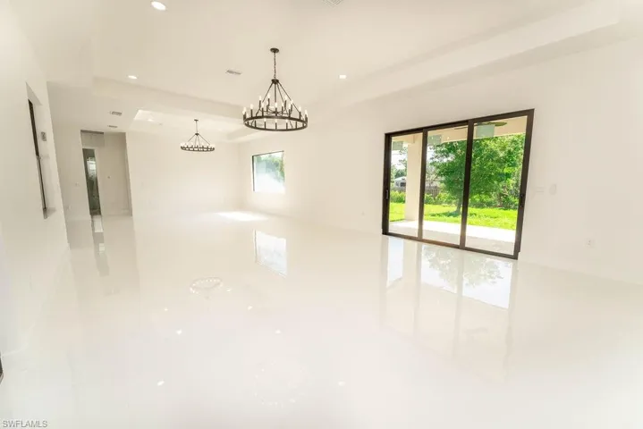 Empty room featuring a tray ceiling, recessed lighting, and a chandelier