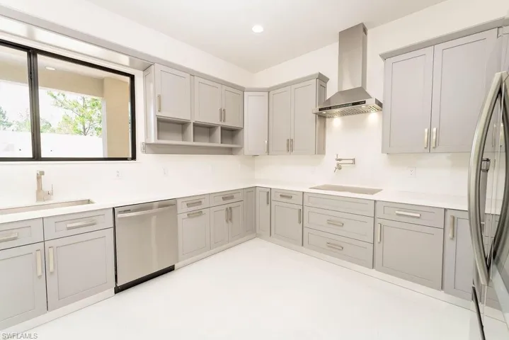 Kitchen with wall chimney range hood, appliances with stainless steel finishes, gray cabinetry, recessed lighting, and open shelves